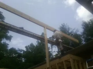 Carpenter setting a ridge beam over a new addition frame — Ice Dam Removal by Roofing Brothers in Helendale