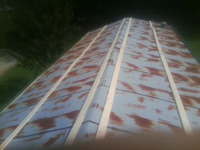 Rusted metal roof panels with new wood purlins before replacement — Storm Damage Roof Repair in Helendale by Roofing Brothers