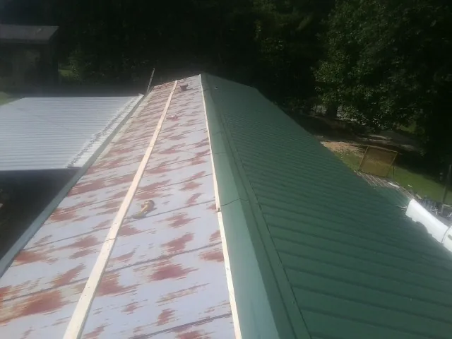 Old rusted panels beside newly installed green metal roofing — Wind Damage Roof Repair by Roofing Brothers in Helendale