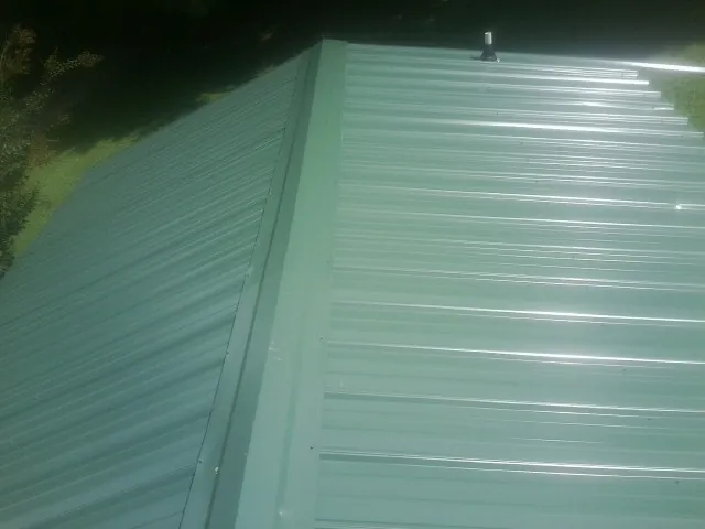 New green metal panels meeting at the ridge of a roof — Flat Roof Repair work by our crew in Helendale
