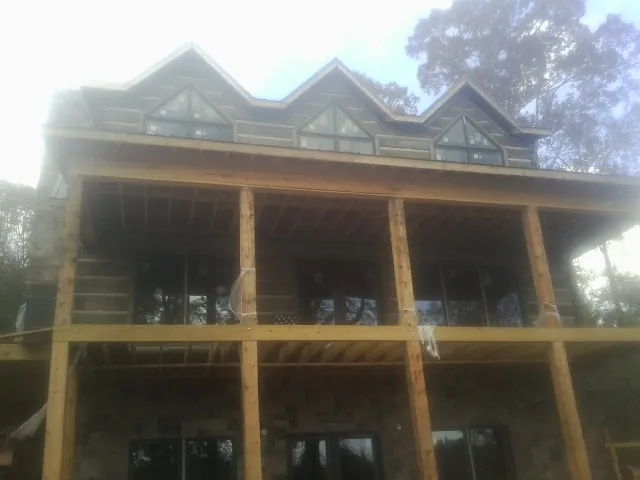 Dormers and porch framing on a large log home under construction — Roof Coating work by our crew in Helendale