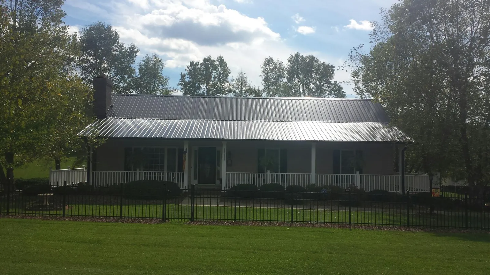 Gray metal roof on a brick ranch with a full width front porch — Gutter Guard Installation work by our crew in Helendale