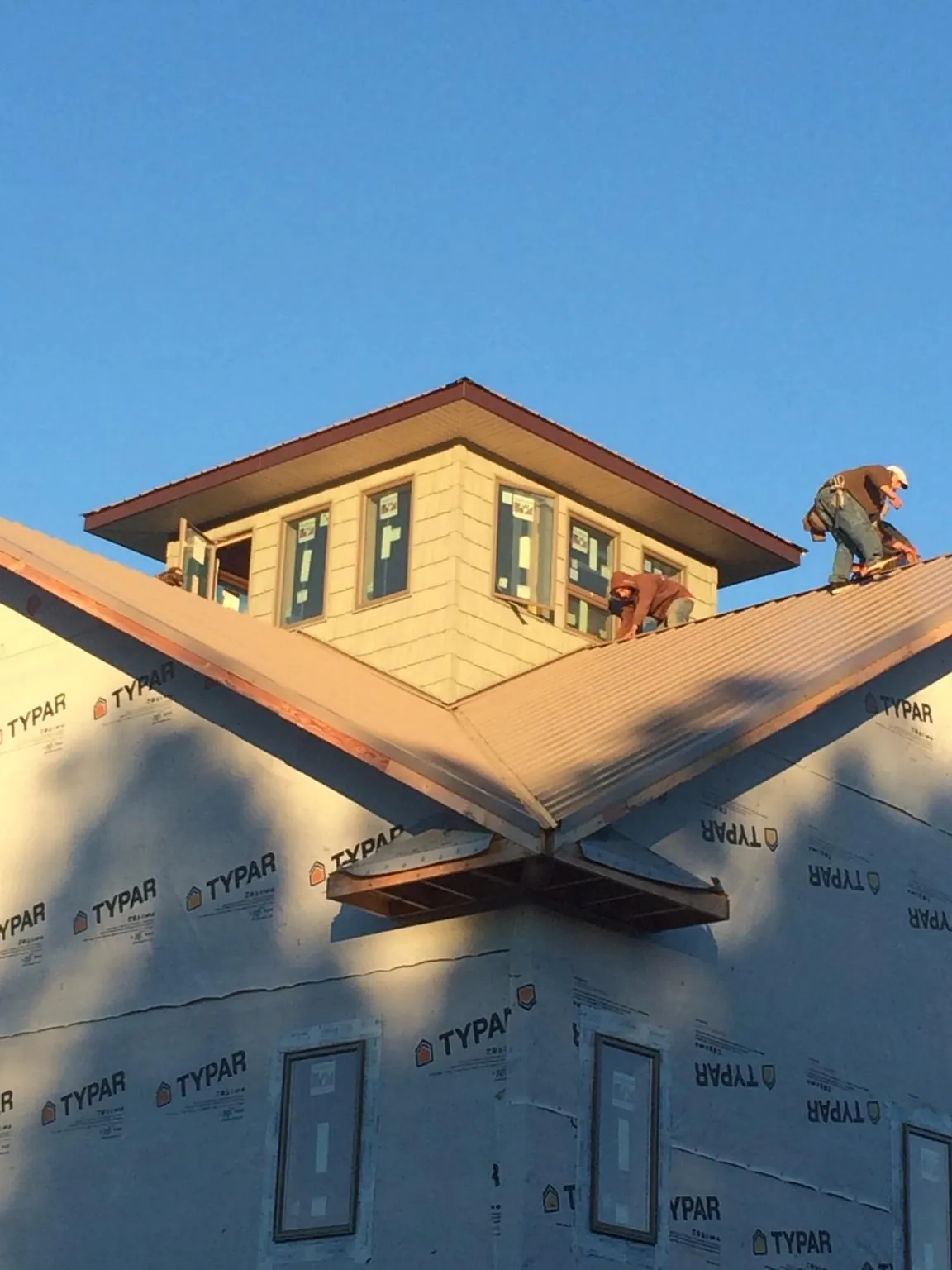 Roofers working around a rooftop cupola on a new metal roof at sunset — Roof Waterproofing in Helendale by Roofing Brothers